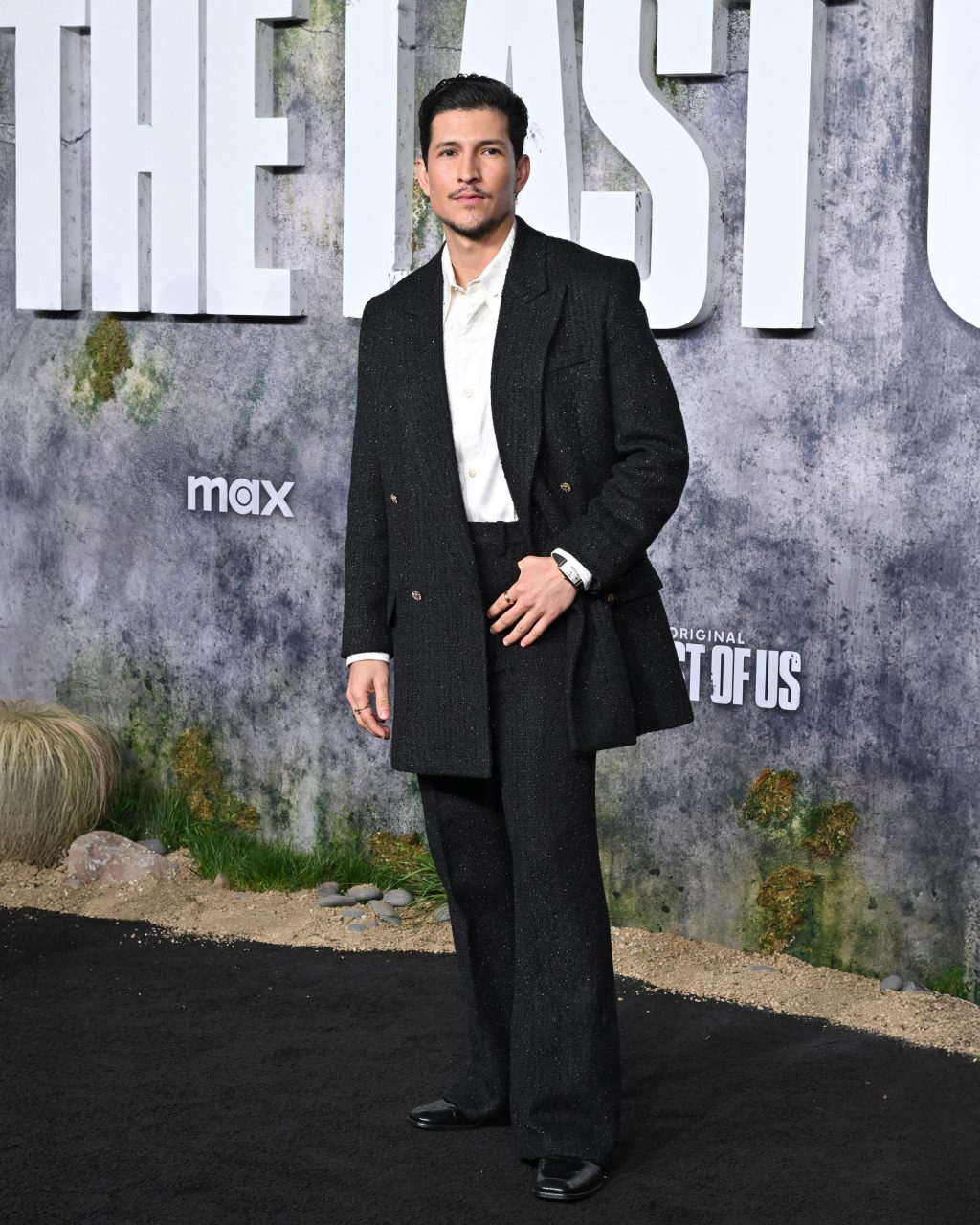 Danny Ramirez poses in a black AMIRI double-breasted suit at The Last of Us premiere in Los Angeles.
